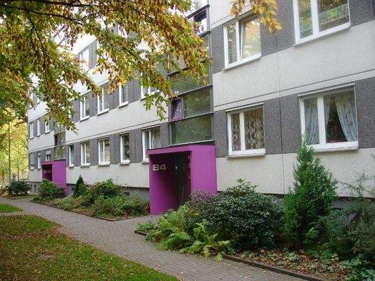 Seitenansicht eines mehrgeschossigen Wohnhauses mit Bepflanzung