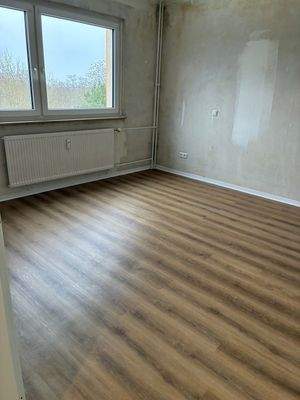 Blick in das Schlafzimmer. Mit Fenster und neuer brauner Vinylboden. Decken weiß angelegt. Wände tapezierfähig.