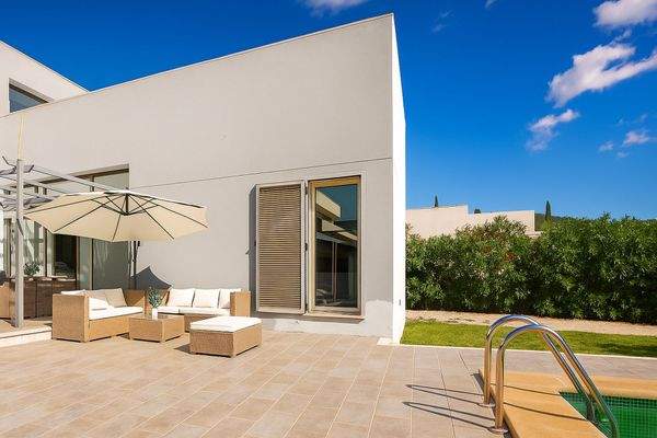 Lounge-Bereich mit Poolblick und mediterranen Pflanzen.