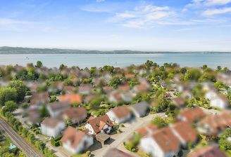 Haus mit Nachbarschaftsbebauung und dem See im Hintergrund