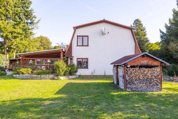 Haus mit Terrasse und Holzlager