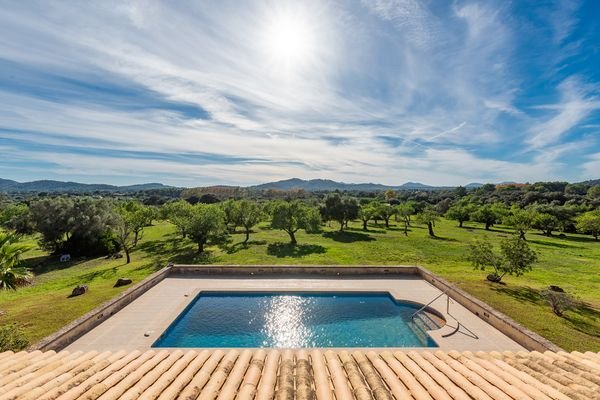 Blick vom Balkon auf den weitläufigen Garten und Pool