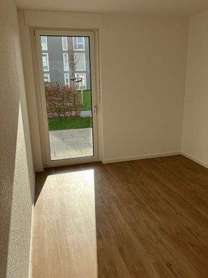 Schlafzimmer mit weiß angelegten Wänden, braunem Vinyl-Designboden in Holzoptik und Zugang zur Terrasse