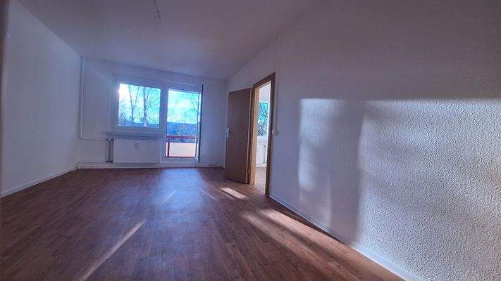 Wohnzimmer mit Zugang zu Küche sowie Balkon