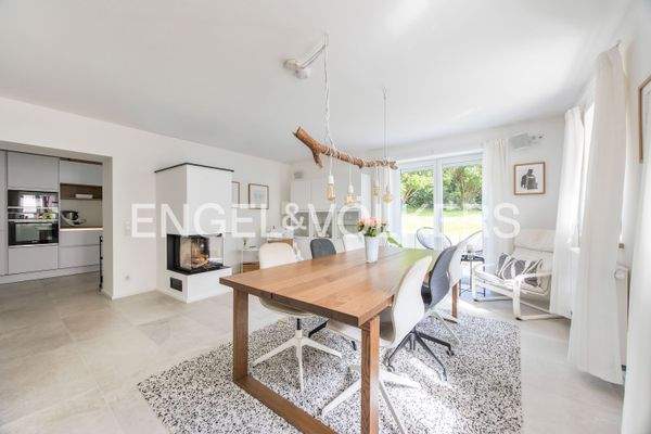 Großzügiges Esszimmer mit Kaminofen, lichtdurchfluteten Fenstern, Gartenaustritt und stilvollem Ambiente