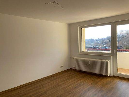 Wohnzimmer mit Zugang zum Balkon und hochwertigem Vinylbelag in Holzoptik