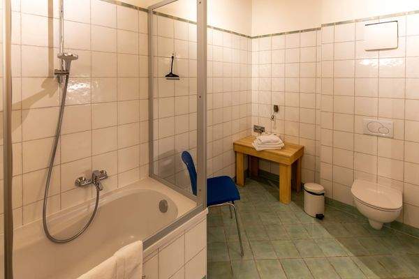 Geräumiges Bad mit Badewanne und WC – schlicht gefliest und mit praktischer Ausstattung.