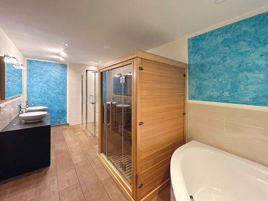 Badezimmer mit Eckbadewanne, Dusche und Sauna