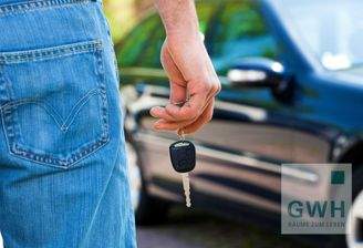 Person mit Schüssel vor Auto.