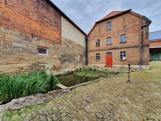 ehemalige Gesindestuben, davor Regenauffangbecken