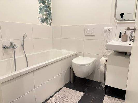 Das Badezimmer mit Wanne, Dusche und Waschmaschinenstellplatz