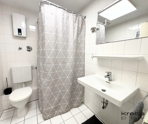 Hell gefliestes Bad mit Dusche