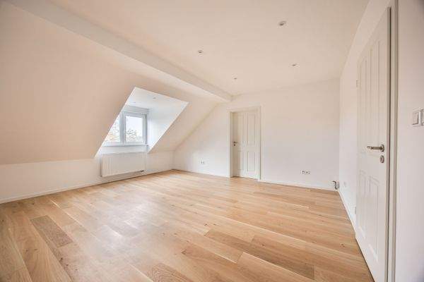 Lichtdurchflutetes Wohnzimmer im Dachgeschoss mit hochwertigem Eichenboden und klarer Raumwirkung