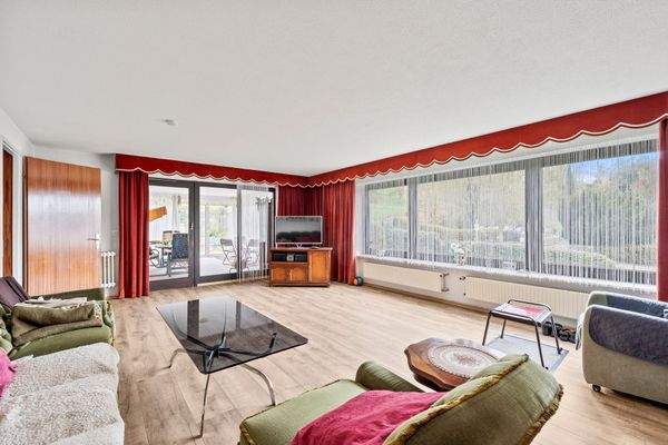 Wohnzimmer mit großer Fensterfront und Ausgang zum Wintergarten