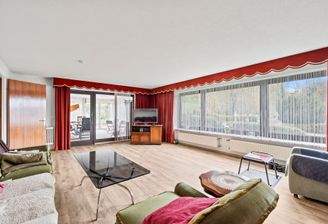 Wohnzimmer mit großer Fensterfront und Ausgang zum Wintergarten