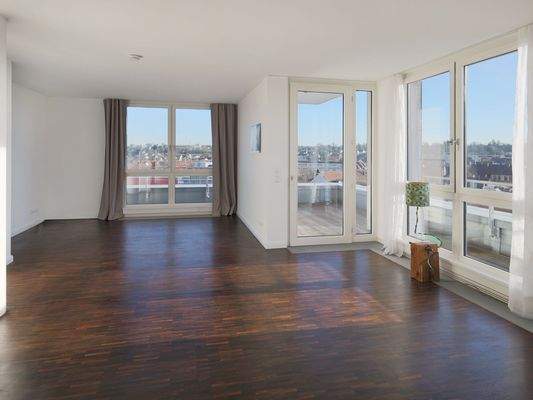 Heller, offener Wohnbereich mit breiter Fensterfront und nahtlosem Zugang zur Dachterrasse