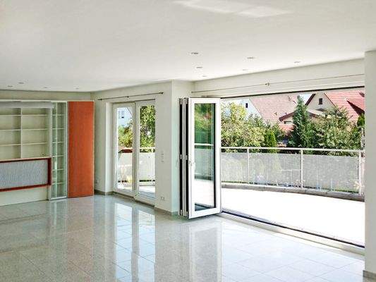 Luftiges Ambiente im Wohnbereich mit Zugang zum sonnigen Balkon mit Gartenblick