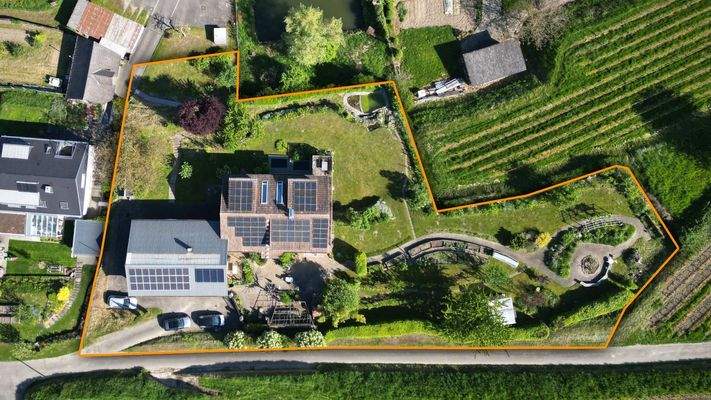 Vogelperspektive auf das Grundstück mit meditarranem Vorgarten, Teich, großer Wiese und vielen Details