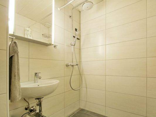 Hell gefliestes Badezimmer mit bodengleicher Dusche und WC