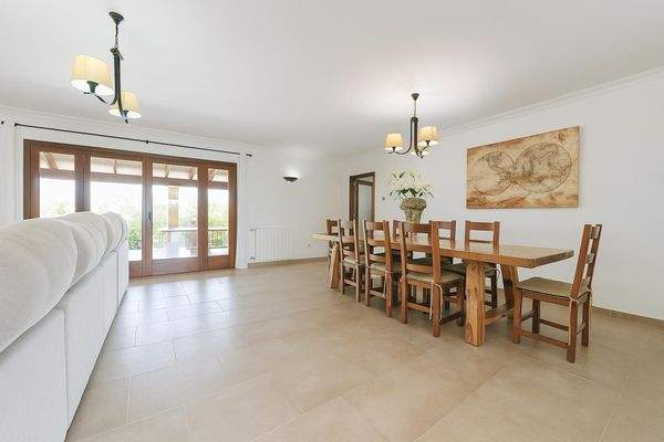 Geräumiger Essbereich mit großem Holztisch und Zugang zur überdachten Terrasse.