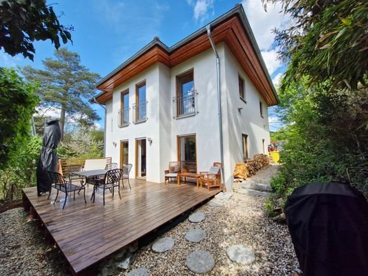 Elegante Hausansicht mit zauberhafter Holzterrasse für Outdoor-Genuss