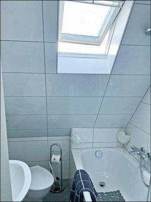 Modernes und hell gefliestes Bad im DG