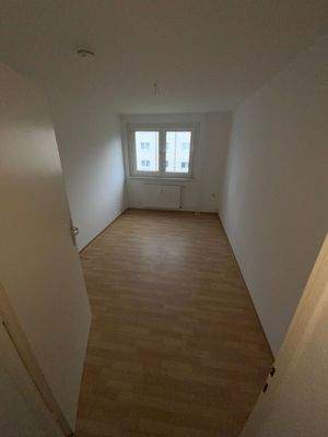 Kinderzimmer mit braunem PVC Boden, weißen Wänden und Fenster.jpg