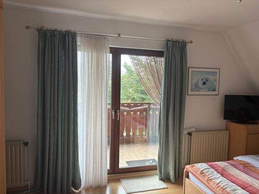 Schlafzimmer im OG mit Zugang zu der geschützten Loggia und Blick in den Garten