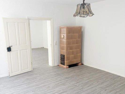 Schlafzimmer mit Kachelofen und Blick Richtung Wohnzimmer