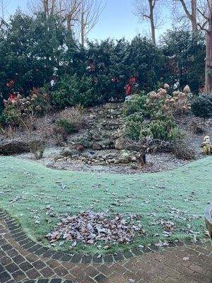 Wasserfall aus Feldsteinen in der bepflanzten Hügellandschaft