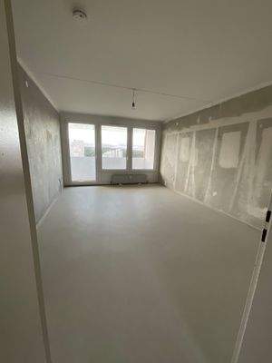 Beispielhaftes Wohnzimmer mit tapetenfreien Wänden und hellem Linoleumboden