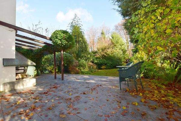 Die erneuerte Terrasse mit Kamin geht über in den privaten Park-Garten