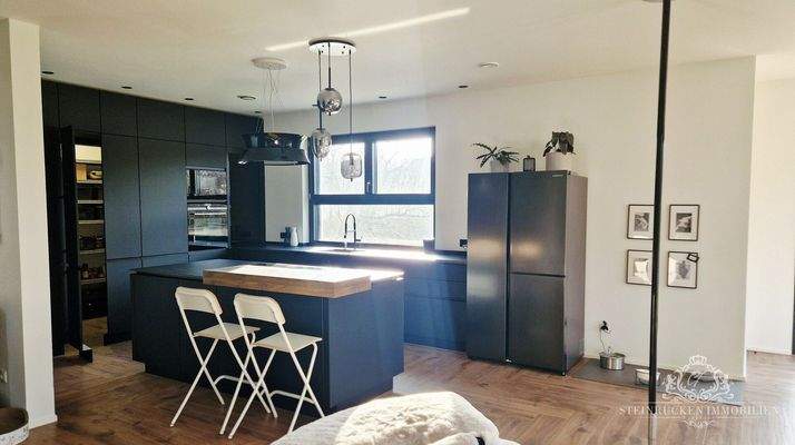 Elegante Premiumküche mit Bar‑Ambiente, großzügiger Kochinsel und verborgener Speisekammer