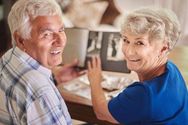 cheerful-senior-couple-browsing-album-with-their-p