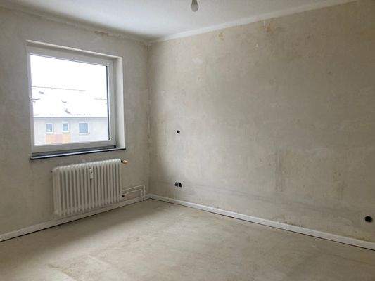 Schlafzimmer mit weißem Fenster und Heizkörper.