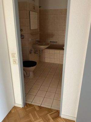 Blick in das Badezimmer mit Wanne, beige Fliesen ohne Fenster