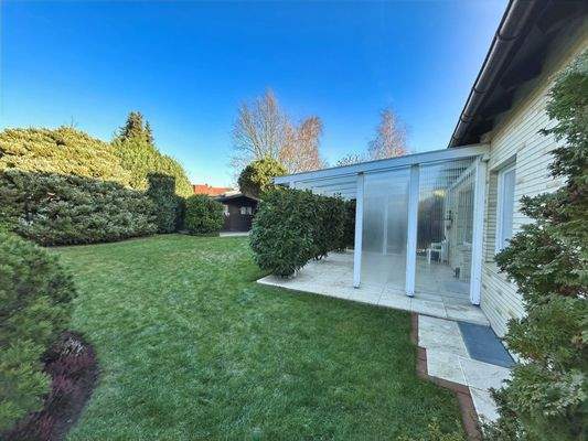 Blick in den Garten auf der Nordseite des Hauses mit überdachter Terrasse und einem Gartenhaus