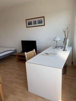 Blick vom Balkon zum Schreibtisch und TV