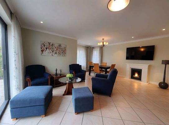 Wohnkomfort mit Charme: Offene Wohnküche mit gemütlichem Kamin und bodentiefen Fenstern