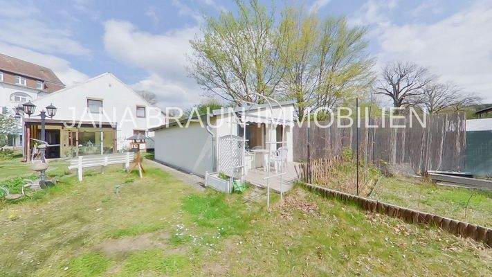 Gartenansicht mit Wintergarten und Nebengebäude