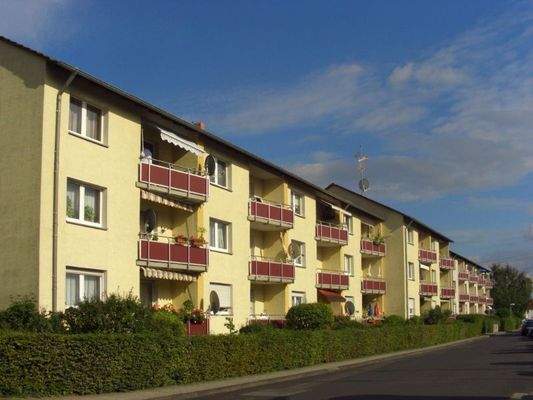 Rückansicht auf das gelb gestrichene Haus mit roten Balkonen.