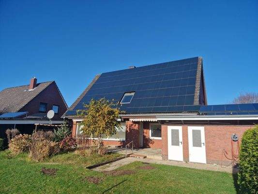 Blick auf die Photovoltaikpaneele und Zugangstüren Keller / Garage