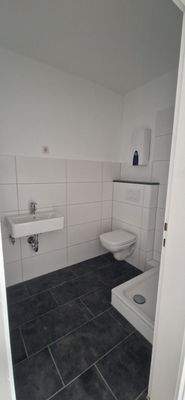 Modernisiertes Bad ohne Fenster, weiße Wandfliesen, anthrazitfarbene Bodenfliesen, Hänge WC, Duschtasse.jpg