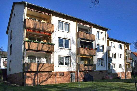 Rückansicht des Mehrfamilienhauses mit Balkonen und Grünfläche