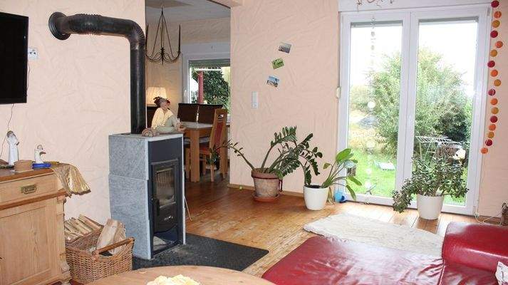 Wohnzimer mit Ofen und bodentiefen Fenstern