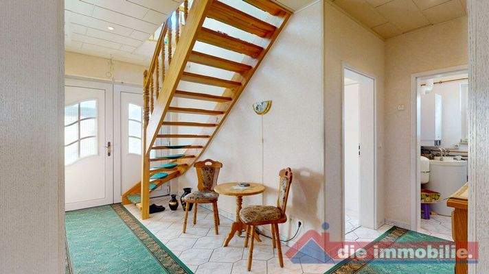 Heller Eingangsbereich mit offener Holztreppe