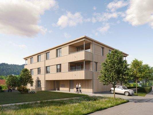 Modernes Mehrfamilienhaus mit Holzfassade, Balkonen und großzügiger Grünfläche unter blauem Himmel (Riedstrasse, Hohenweiler).