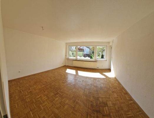 Großes Wohnzimmer mit Parkettboden und Balkonzugang 