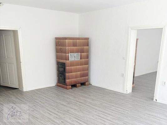 Wohnzimmer mit Kachelofen und Blick Richtung Schlafzimmer