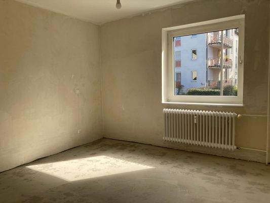 Schlafzimmer mit weißem Fenster, Heizkörper, ohne Boden und tapetenlos.